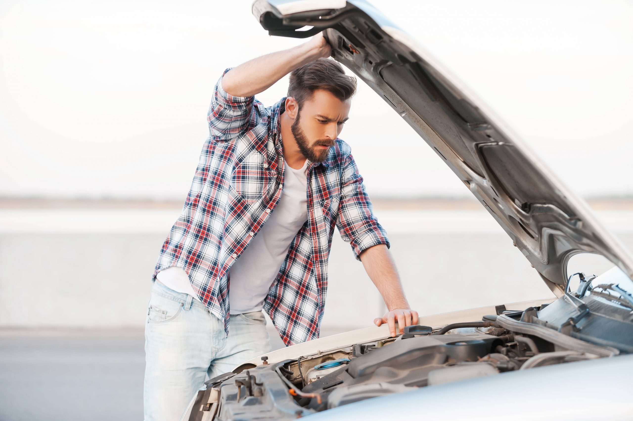 Car repair mistakes, man looking under the hood of a car.