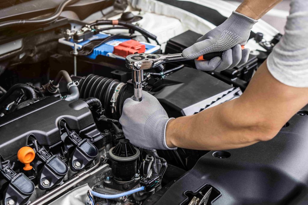 Save money on car repairs, hands in safety gloves working on car's engine.