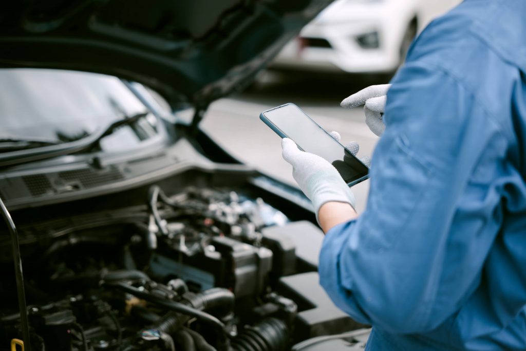 Car repair mistakes, man checking his phone for instructions on car repairs.