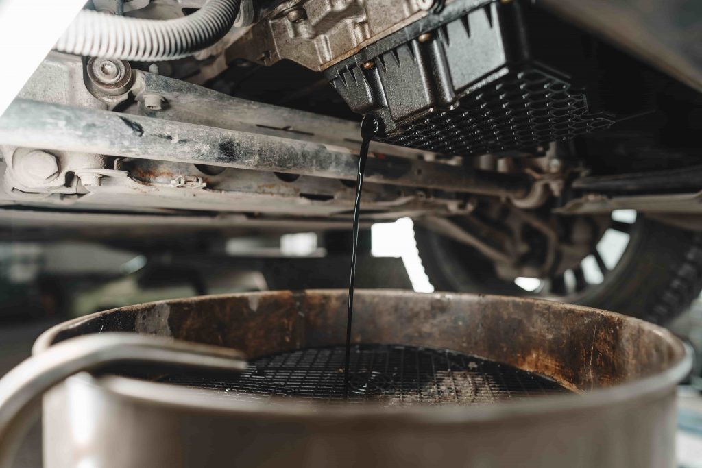 DIY car oil change, draining car oil in an oil pan.