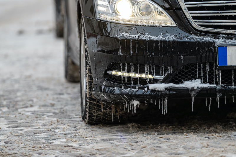 Winter car repairs, car bumper covered in icicles.