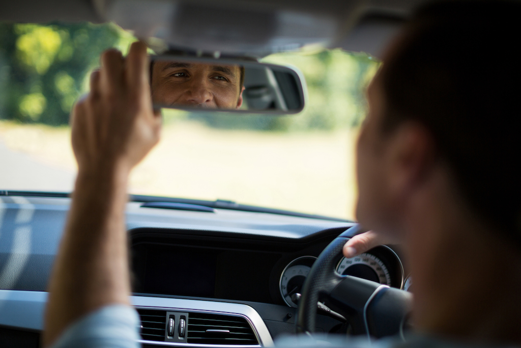 Brake safety, person adjusting rear view mirror.